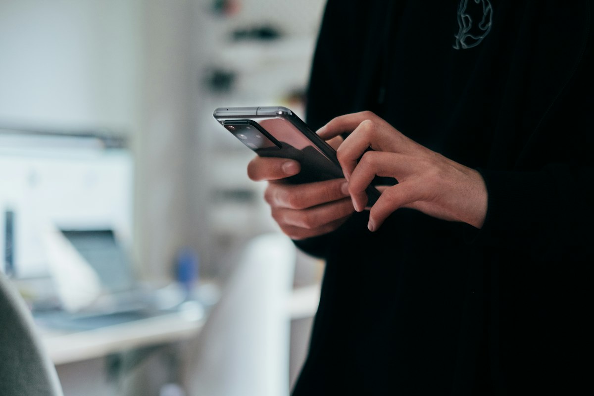 A person holding a smartphone, illustrating the choice between upgrading and keeping a current phone