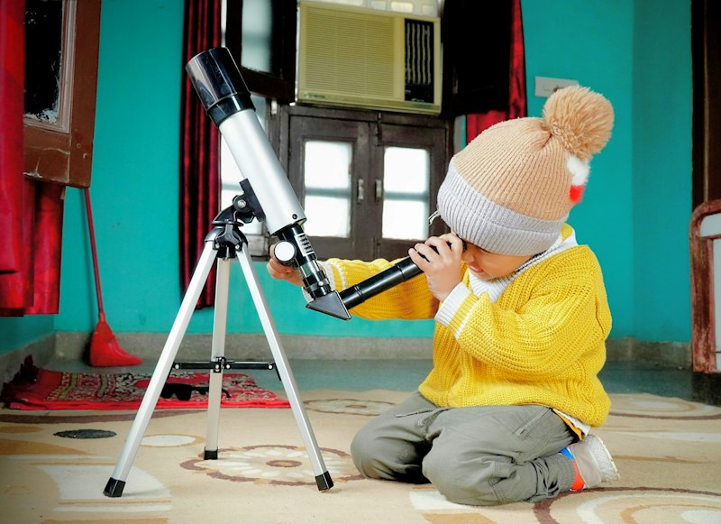 A young student looking through a telescope while learning about space science
