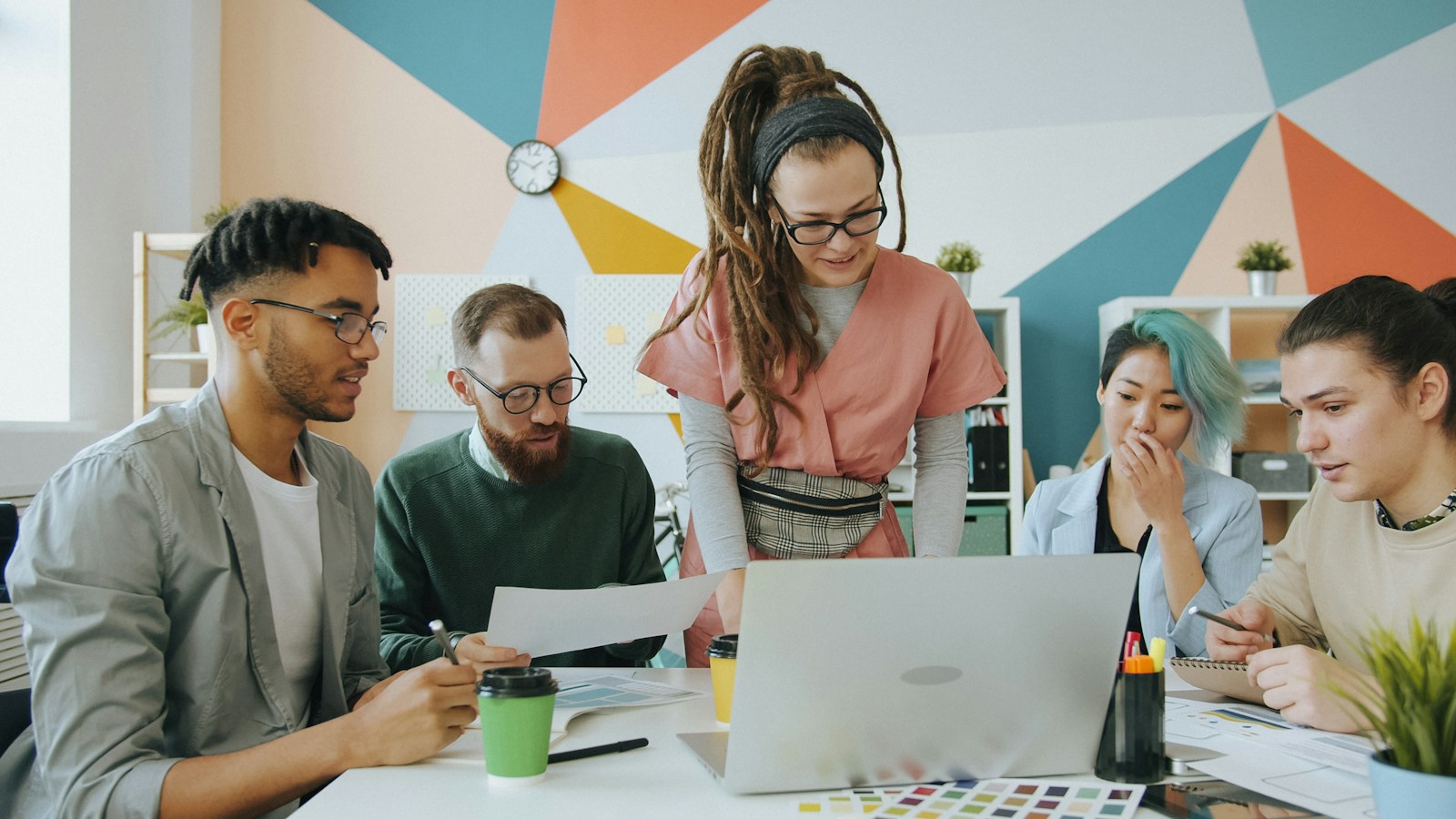 Creative professionals collaborating around a laptop on an advertising campaign